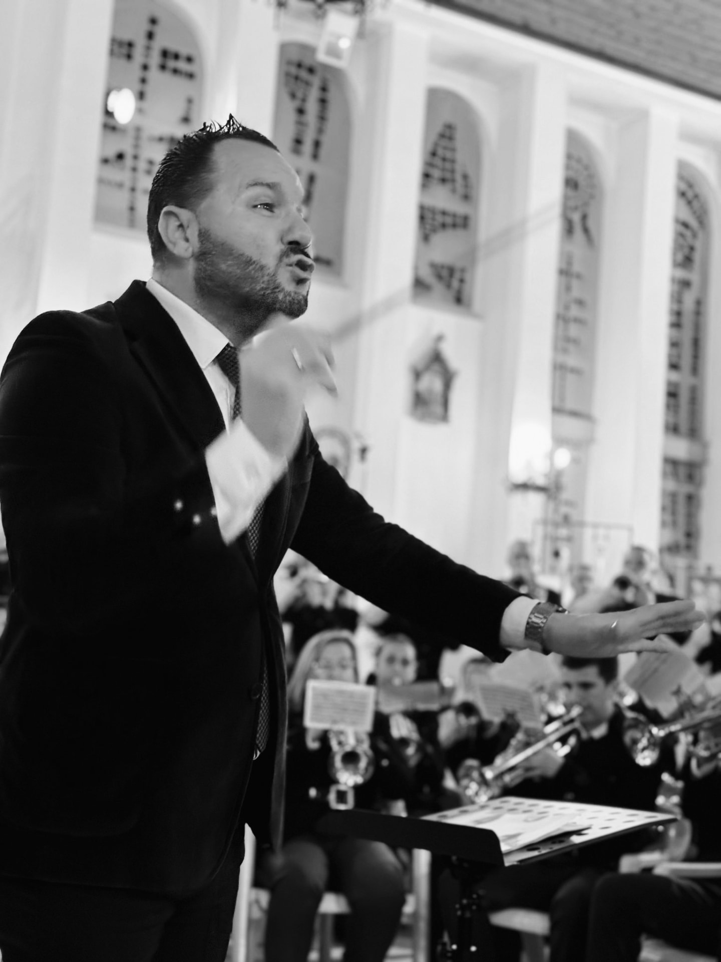 Retrato en blanco y negro dirigiendo con gesto expresivo en un templo
