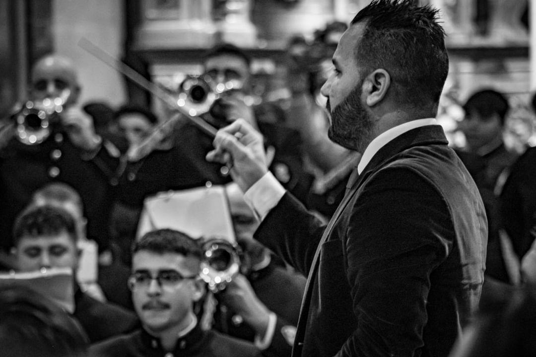 Dirección con batuta frente a la sección de trombones en un templo