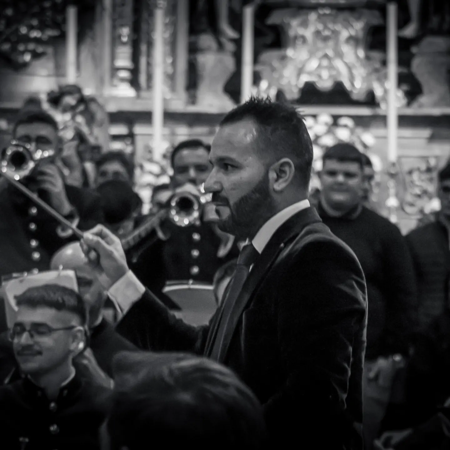 Dirección de la banda con batuta alzada ante el retablo