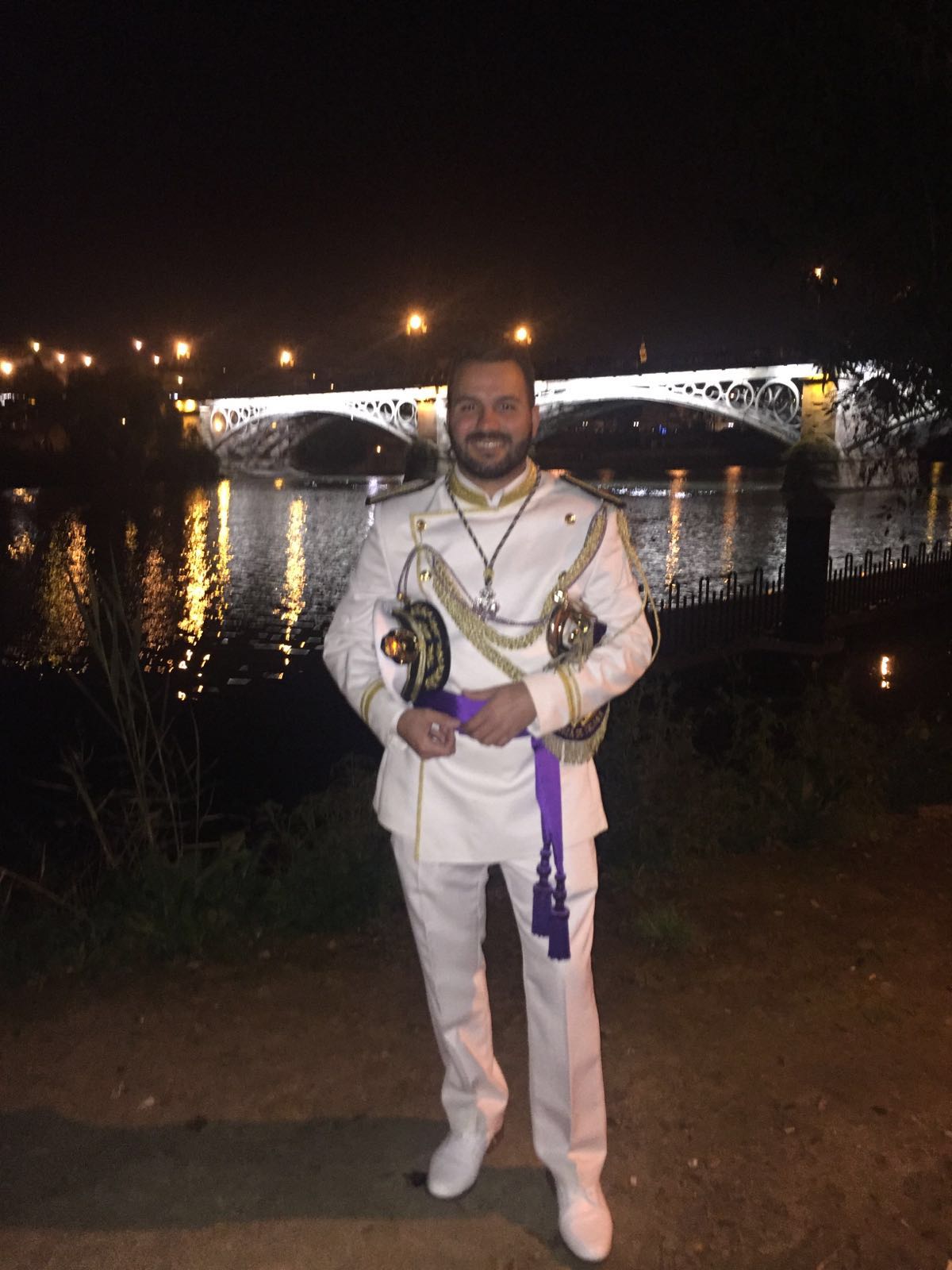 Manu Guerrero con uniforme blanco ante el puente de Triana iluminado